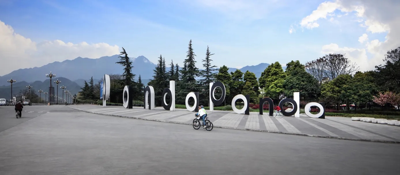 Large white and black letterforms across a plaza with mountains behind