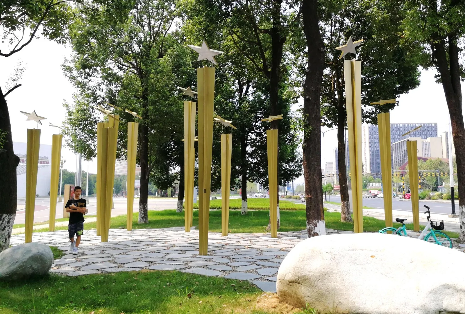 Golden star poles standing in a stone-paved garden under trees