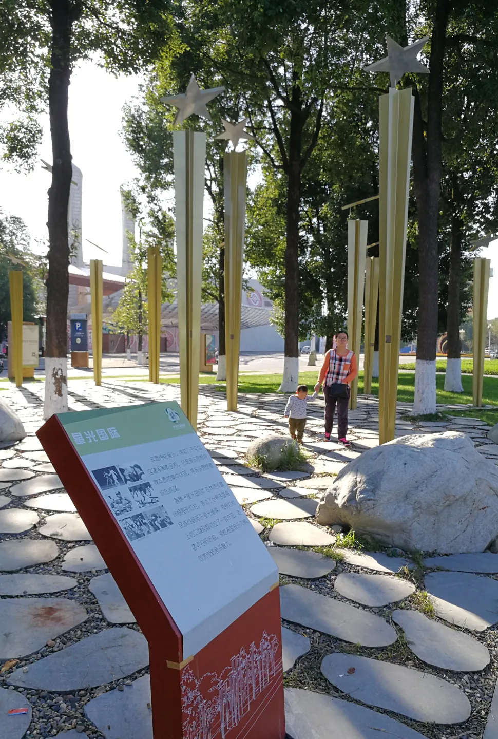 An interpretive sign beside the stone path and poles